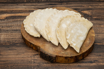 Frozen chebureks on wooden table