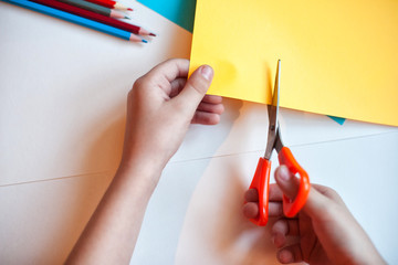The child cuts out the application of Colored pencils on a background of white and colored paper. Colorful pencil on a white background. Children use these pencils as home activities and applications.