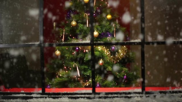 Christmas Tree in Window at a house with snow falling outside. Snowing. Tracking Shot Towards. Stock Video Clip Footage