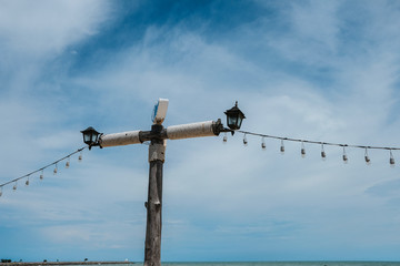 Wooden electric pole on the beach on blue sky background.