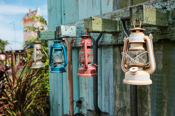 old shovel or hoe handle with colorful lamp or retro lantern hang on vintage green blue wood wall with plant for farmer and agriculture tool or gardener at countryside on labor or labour day in summer