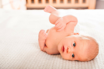 Newborn on a white plaid close-up. The baby is looking and copy space. Baby care concept.
