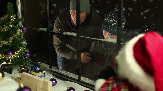 Father and Son looking into a shop Window at Christmas with snow falling. Tracking shot. Stock Video Clip Footage