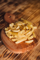 Tasty french fries on cutting board, on wooden table background