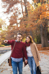 Fototapeta premium Portrait of a couple in the park holding hands and enjoying autumn.