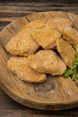 Frozen nuggets  on a wooden plate on a wooden background