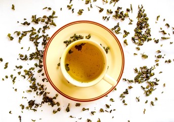 Aromatic green dry tea spread on the table. Top view of green tea served with tea cup.