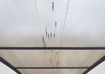 Close-up of Roof of transparent corrugated plastic sheets. Industrial construction. White rusty coating with black iron bars.
