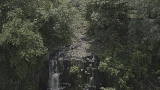 man approaching a waterfall in the forest