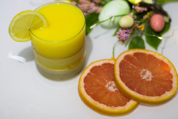 Orange juice in a glass with slices of lemon and grapefruit on a light background