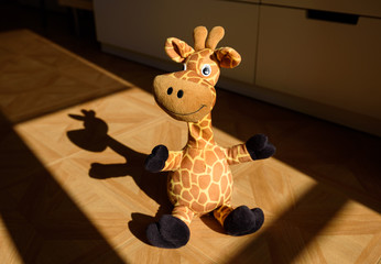 Cute standing giraffe stuffed plush in a child's room illuminated by sunlight coming from the...