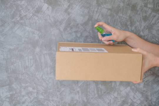 woman using spray alcohol sanitizer cleaning parcel post to prevent virus and bacterias from Postal sender she protects herself and her family from virus woman giving package