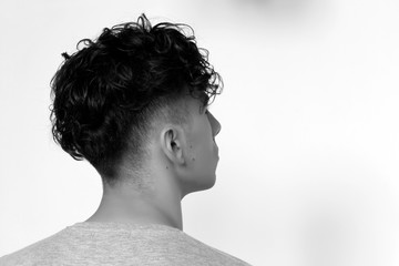 Cool, young hipster guy with short curly hair is posing in studio on isolated background. Style,...