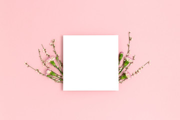 Frame made of flowers on a pink pastel background. Paper card mockup. Holiday concept.