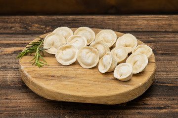 Frozen dumplings with meat on a wooden plate on a wooden background