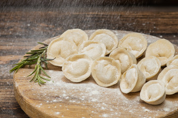 Frozen dumplings with meat on a wooden plate on a wooden background