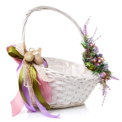 Brown wicker basket with original handle. Decor with flowers, eggs and ribbons. Isolated on a white...