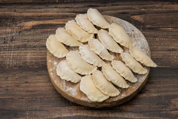 Frozen dumplings on a wooden plate on a wooden background