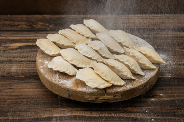 Frozen dumplings on a wooden plate on a wooden background