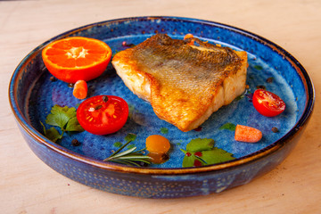 cooked fried fish on a plate with vegetables