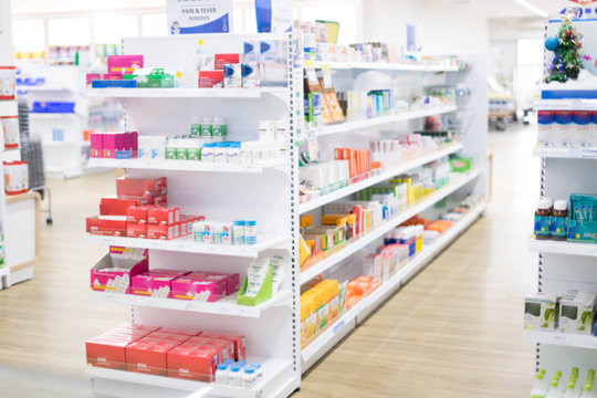 At the chemist, Medicines arranged on shelves, Pharmacy drugstore retail Interior blur abstract background with medicine healthcare product on cabinet with warm light.