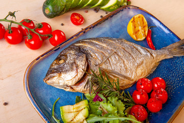 cooked fried fish on a plate with vegetables
