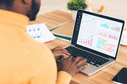 Black entrepreneur analyzing graph on laptop at workplace