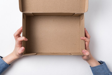 Children's hands holding an open cardboard box. Empty box, white background.