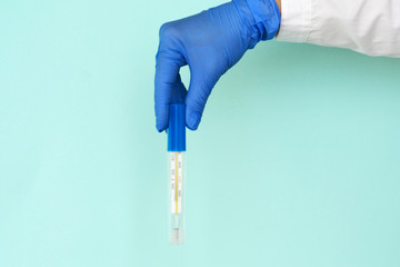 hand in latex gloves holds a medical mercury thermometer