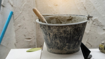 Mix the cement in a small bucket for the construction beside the house wall. © ArLawKa