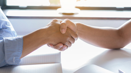 Obraz premium The two men shook hands to make a deal for his business by the window.