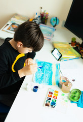 Casual student doing homework. Isolated on white backgroundA set of a collection of baby artist accessories. Canvas, watercolors, art brushes, and a white open notebook lay on a white table.