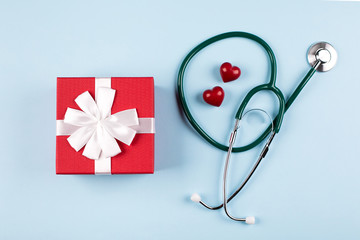 National Nurse Day Holiday Background Flat lay with red gift box, medical stethoscope and two red hearts. Healthcare medicine concept. Top view, flat lay.