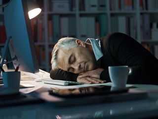 Office worker sleeping on the desk late at night