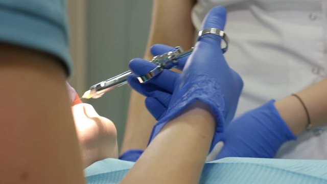 Female dentist applying anesthetic injection before oral treatment. injection to patient in dental clinic. Close-up shot of Dental cure. Medicine, dentist, and health care concept. 4k footage - Powered by Adobe