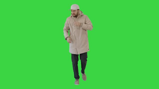 Man in winter outfit walking and coughing on a Green Screen, Chroma Key.