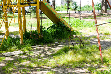 Fototapeta na wymiar An empty playground. Quarantine, isolation, empty playgrounds, overgrown with grass, no one, no children. Old abandoned children's playground