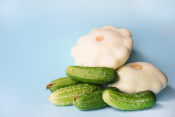 Vegetable minimal concept. Cucumbers and pattypan squash on a light blue background with copy space for text.