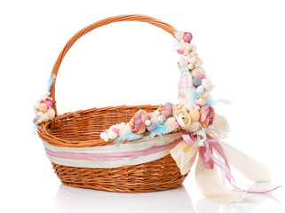 Fototapeta na wymiar Brown baby wicker basket for Easter celebration. Bright delicate pink floral decor with ceramic decorative bunny.
