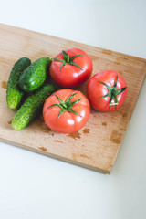 Fresh tomatoes and cucmbers on the wooden table with white background