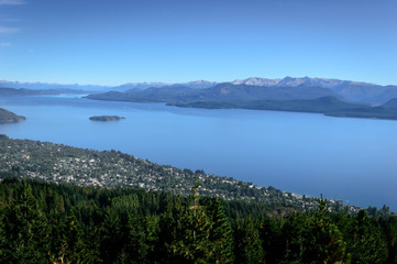 Landscape with lakes between mountains and pine trees. On top of a mountain in Bariloche, Argentina. A sunny summer day.