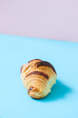Obraz na płótnie Canvas One croissant on a blue background, overhead view.