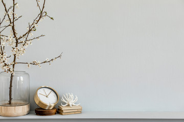 Minimalistic composition on the shelf with dried flower in design vase, gold  clock, book and...