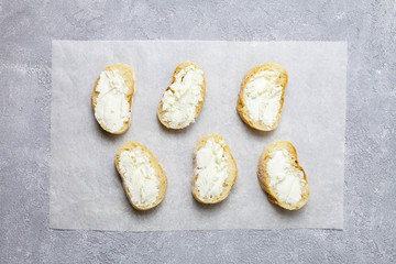 Six toast with cream cheese on grey background, top view