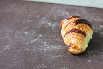 One croissant on a blue background, overhead view.