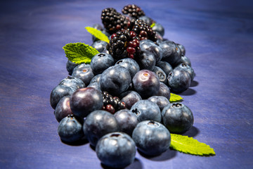 Blueberries and blackberries on dark violet background.