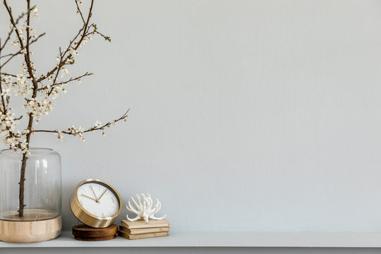 Minimalistic composition on the shelf with dried flower in design vase, gold  clock, book and decoration. Grey wall. Copy space.