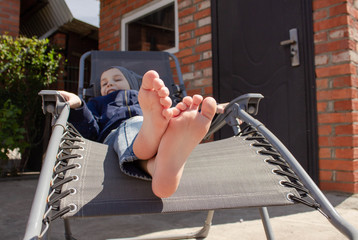 the boy's bare feet on the chaise longue. resting boy in the sun. The concept of relaxation. © Ekaterina