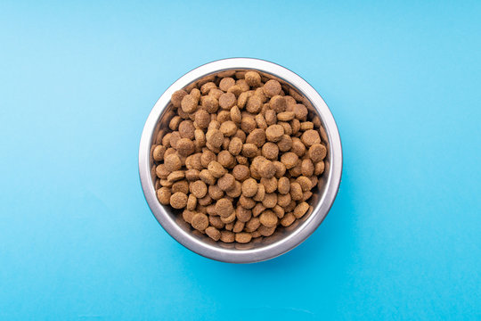 Dog Food In A Metal Bowl. Blue Background. From Above