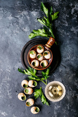 Baked snails with garlic butter and fresh herbs in a frying pan, selective focus